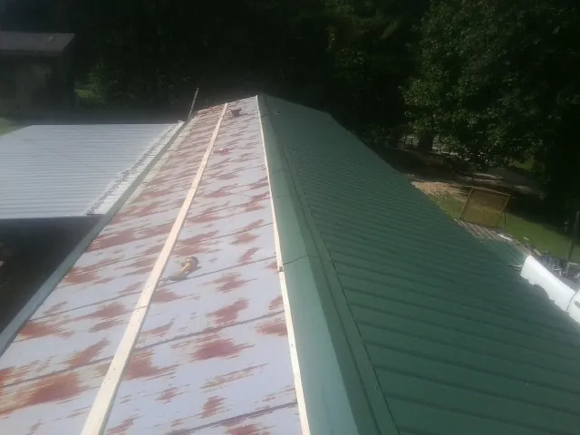 Old rusted panels beside newly installed green metal roofing — Wind Damage Roof Repair by Roofing Brothers in Midway